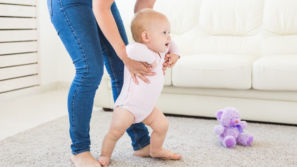 Baby standing while parent trying to him her walk.