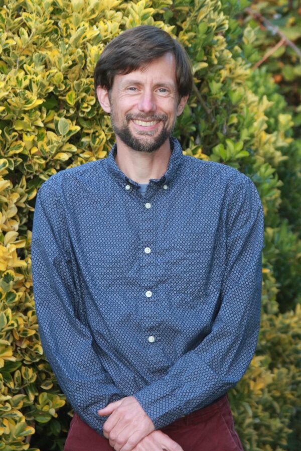Trevor E. Carlson, PT, DPT. Author of Tummy Time to Walking. Standing in front of bush.