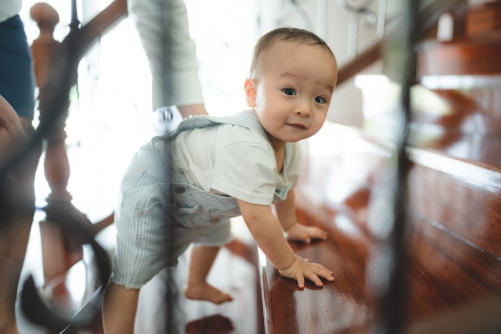 Baby climbing down stairs backward with parent nearby