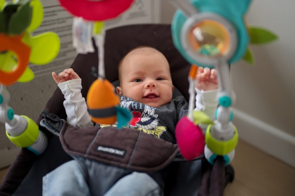 Baby in car seat with toys attached.