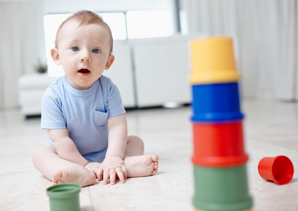 Baby sitting on the floor playing with colorful stacking cups
