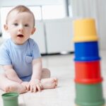 Baby sitting on the floor playing with colorful stacking cups